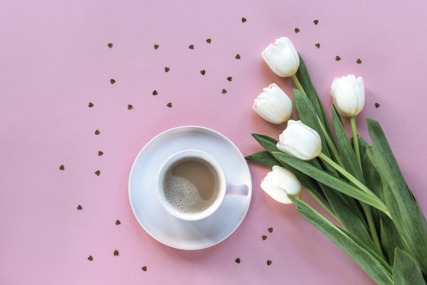 咖啡杯，白色郁金香，粉色背景上的心形纸屑。情人节，春假概念。俯视图，平面布局图片下载