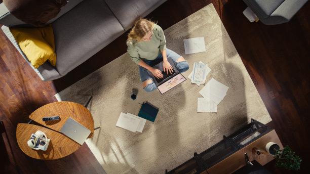 公寓:年轻女子坐在客厅地板上，用笔记本电脑工作。有远程访问的专业女孩在家远程工作。从事电子商务、网上购物的自由职业者。前视图。图片下载
