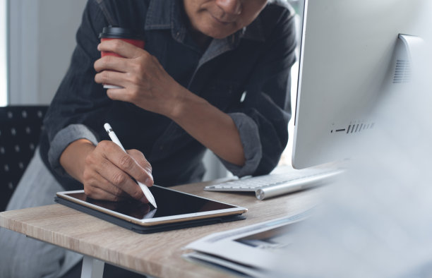 平面设计师，在现代办公环境下使用台式电脑和平板电脑工作图片下载