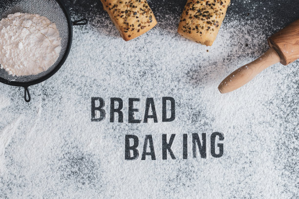 面粉上的铭文:烤面包，擀面杖，筛子和面包在桌子上。图片下载