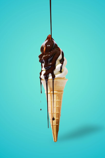 垂直拍摄的冰淇淋筒，巧克力滴在蓝色的背景上图片下载