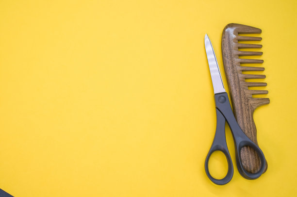 黄色背景上的梳子和剪刀的俯视图图片下载