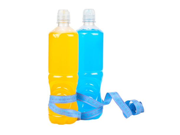 两个装着橙色和蓝色等张力饮料的塑料瓶被包裹在一个测量厘米的白色背景上。图片下载