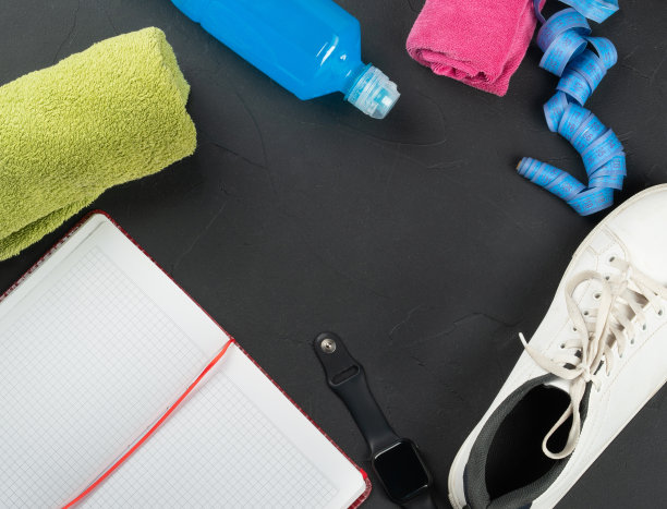健康的概念。毛巾，运动鞋，一瓶等张饮料，记事本，智能手表，黑色混凝土背景上的卷尺，俯视图。本空间图片下载