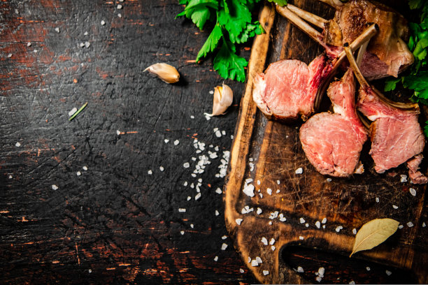用欧芹把烤羊肉放在木砧板上。图片下载