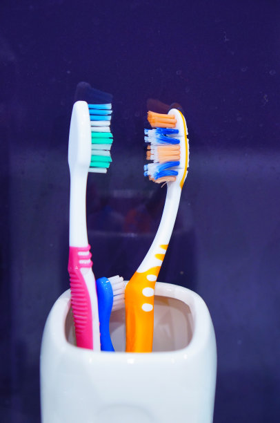 垂直拍摄的三个牙刷在一个白色的杯子图片下载