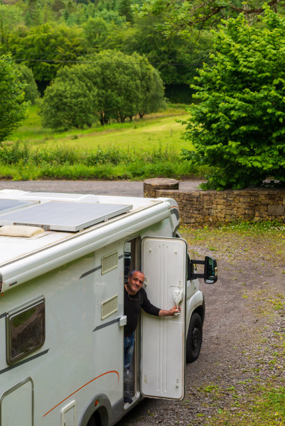 一个男人站在森林边的房车门口图片下载