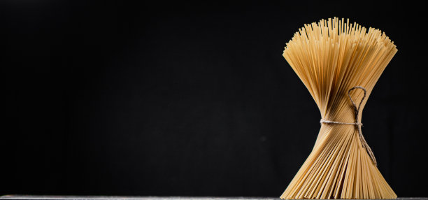 桌子上放着一捆用绳子扎着的干意面。图片下载
