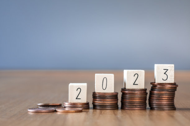 木立方2023年的顶部堆叠硬币与天蓝色的背景和复制空间。为2023年的新年投资存钱和理财计划概念。图片下载