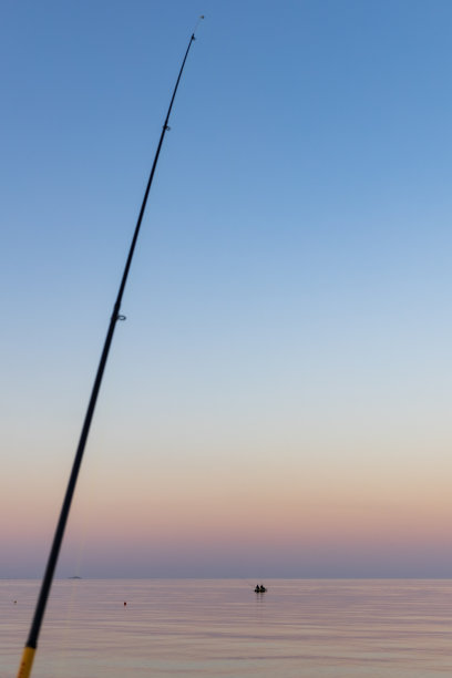 落日余晖下，海面平静，钓鱼竿图片下载