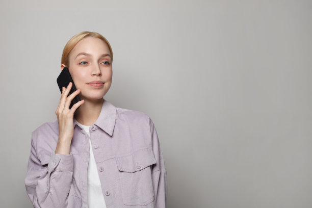 金色头发的随意女子拿着白色背景的智能手机，工作室肖像图片下载