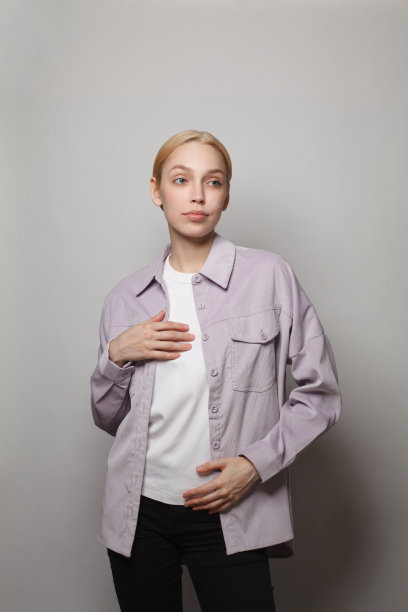 年轻的女模特女人穿着休闲衬衫站在白色的工作室墙壁背景图片下载