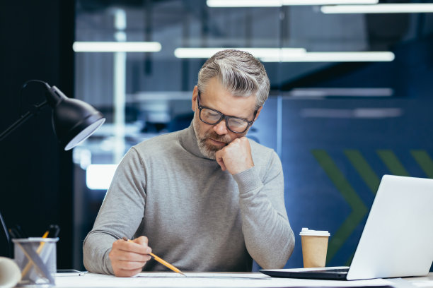认真思考的建筑师设计师在图纸上工作，成熟的人在办公室里工作，工程师在什么东西上设计图片下载