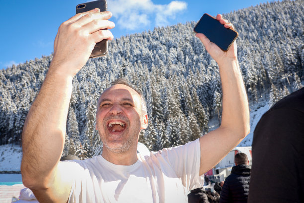 快乐的男子举起双手用智能手机自拍图片下载