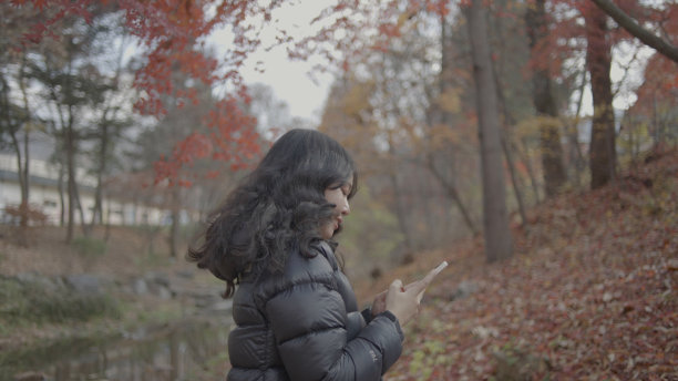 在韩国首尔的一个阳光灿烂的日子里，一位亚洲游客正在公园里欣赏美丽的景色。图片下载