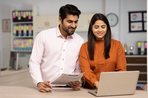 两个商人在一个现代化的办公室里一起使用笔记本电脑处理文书工作。库存图片图片下载