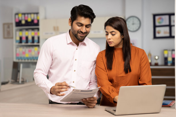 两个商人在一个现代化的办公室里一起使用笔记本电脑处理文书工作。库存图片图片下载