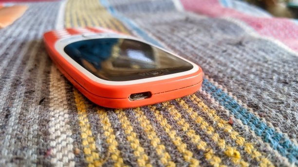 一个键盘电话与按钮隔离在黑色背景。黑色显示屏的旧手机。印度2g、3g橙色手机特写。技术和社会观念。图片下载