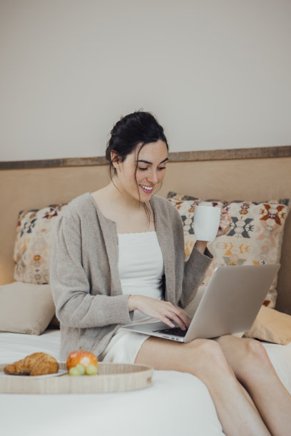积极的女人在床上使用笔记本电脑图片下载