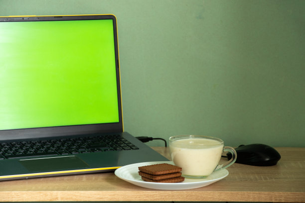 绿色屏幕的笔记本电脑酸奶和饼干放在家里房间的桌子上，工作场所图片下载