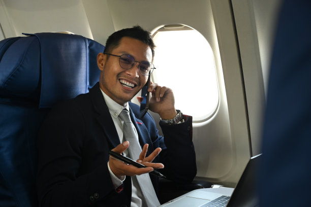 成功的商人乘客坐在机舱靠窗的地方打电话。图片下载
