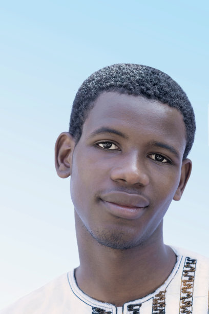 一个微笑的年轻人穿着传统的白衬衫，19岁，户外，晴天，蓝天，照片图片下载