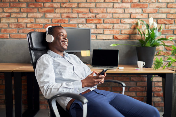 在办公室工作的休息时间，年轻的商人坐在椅子上听音乐图片下载