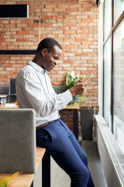 快乐的年轻商人在小办公室使用手机浏览互联网图片下载