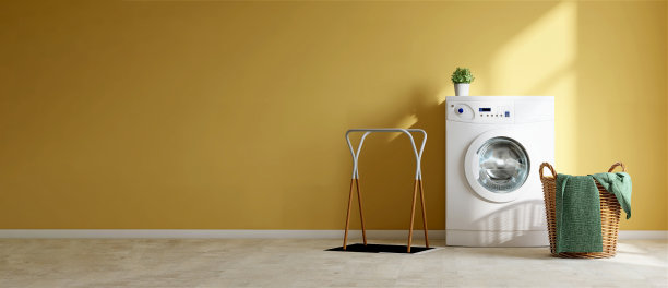 白色现代洗衣机，藤条篮子，毛巾和布架在空的充满活力的黄色墙壁洗衣房图片下载