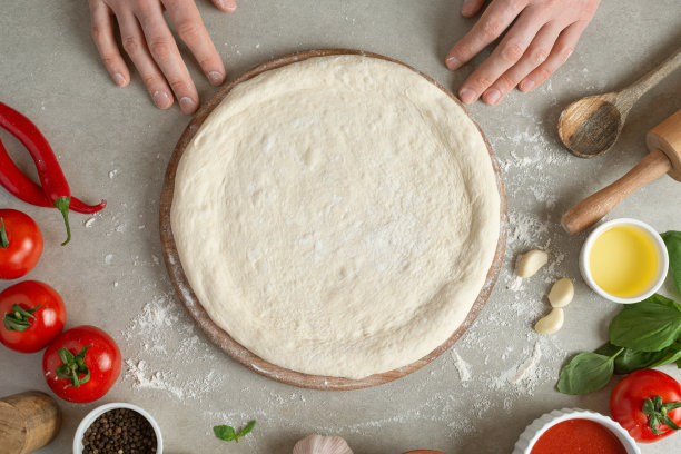制作玛格丽塔比萨饼的过程。男性手，俯视图。番茄酱和奶酪。图片下载