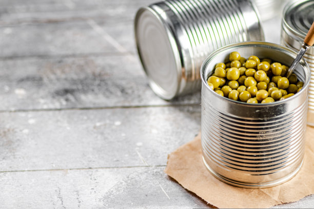 用勺子打开装有绿豌豆罐头的罐头。图片下载