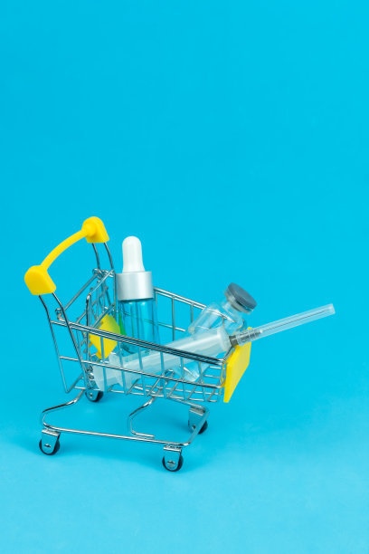 购物车里有蓝色背景的医疗安瓿和注射器，复制空间。购药观念，提高药价。垂直图图片下载