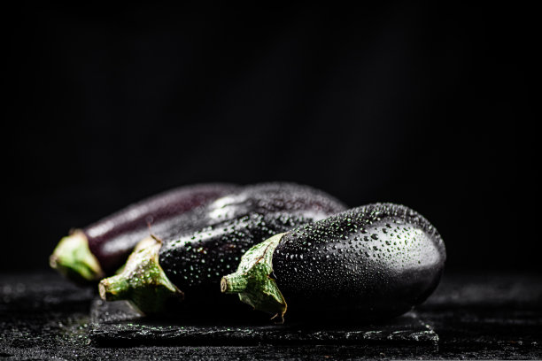 新鲜成熟的茄子，水滴在石板上。图片下载