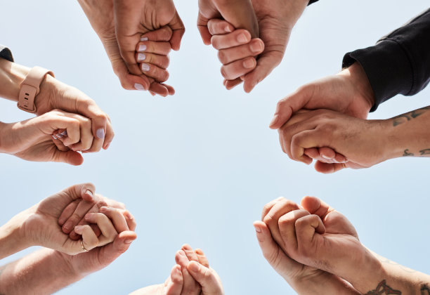 爱、信任、情侣们手牵着手围成一个圈，以表达支持、多样性和浪漫的本质。甜蜜，浪漫，多种族的手在户外蓝天的背景下团结在一起。图片下载