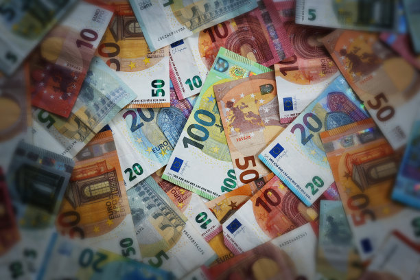 许多不同的欧元纸币，照亮的焦点在百欧元纸币的中间，黑暗和模糊的边缘，金融，商业和经济的概念，高视角图片下载