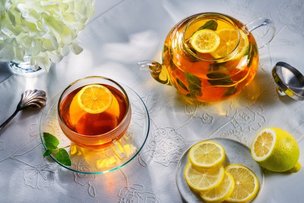 薄荷柠檬茶放在桌子上，白色桌布和茶壶作为背景。前视图。图片下载