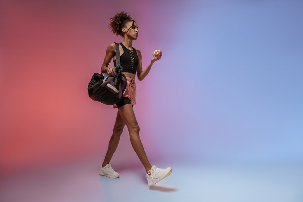 女运动员拿着水瓶、运动包和苹果，背景是演播室图片下载