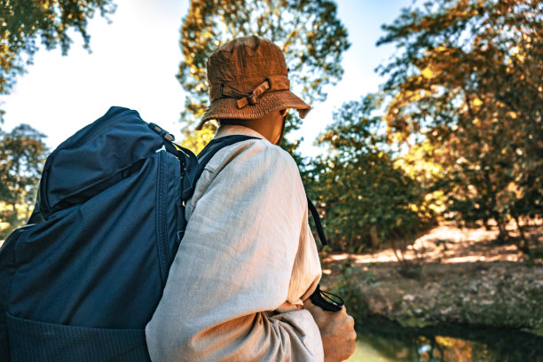 一名年轻的背包客男子在夏天日落时分徒步登山时的背影。活跃的男人感到放松，喜欢独自在美丽的森林里旅行。图片下载