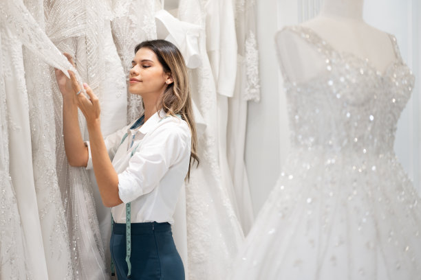 白人女时装设计师在婚礼沙龙检查婚纱图片下载