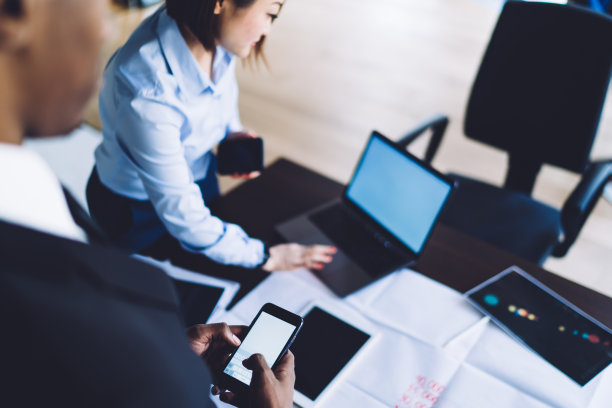 不同的同事使用智能手机和笔记本电脑在办公室创建演示文稿图片下载