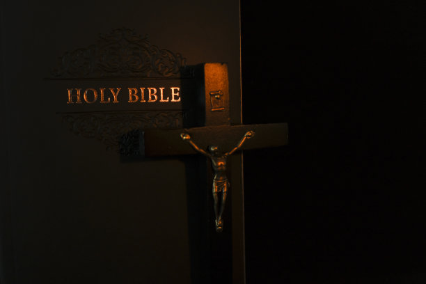 十字架上的耶稣基督和烛光下的圣经。宗教圣书。基督教和天主教信仰的象征。宗教的象征。图片下载