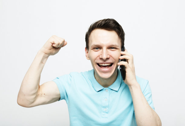 快乐的年轻人在衬衫手势和微笑，同时打电话图片下载