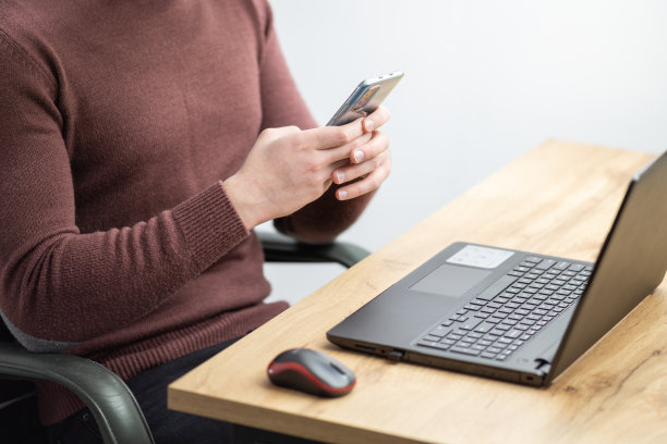 特写一个人在笔记本电脑和使用智能手机工作。图片下载