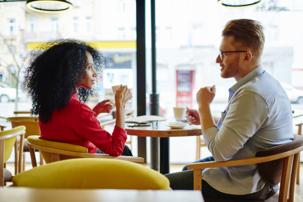 冷静的多种族放松情侣在现代咖啡馆休息时喝热饮图片下载