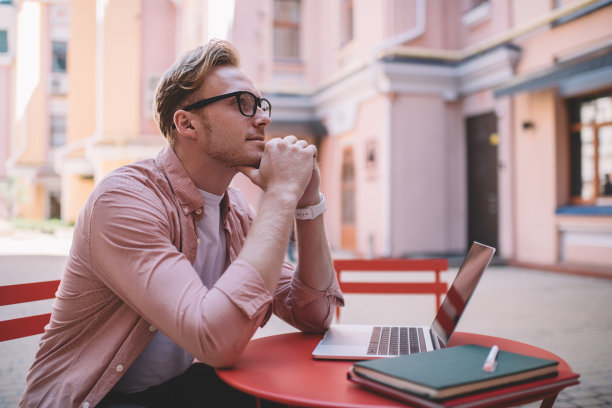 深思熟虑的男性自由职业者坐在街头咖啡馆图片下载