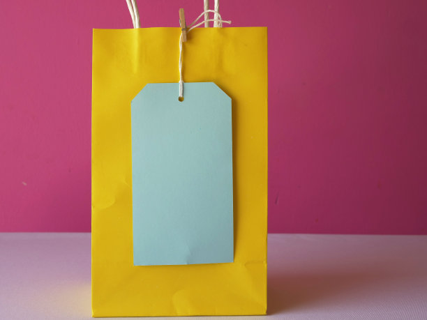 黄色礼品袋和标签在粉红色的背景图片下载