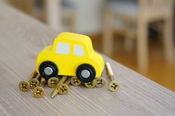 在金属螺丝上的黄色木制汽车玩具的特写图片下载