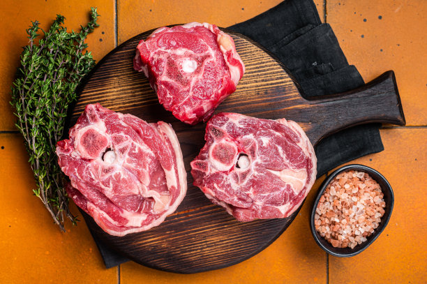 生羊颈排，新鲜的羊肉放在砧板上，配上香草。橙色背景。俯视图图片下载