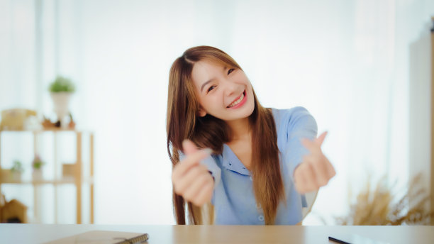 快乐的青少年亚洲女孩博主微笑和心手与网络摄像头录制vlog，社交媒体影响者流媒体，在家里进行视频通话图片下载