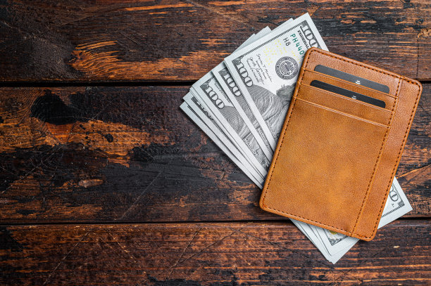 一张一百美元的钞票，放在一个棕色皮夹里，还有信用卡。棕色的背景。前视图。本空间图片下载